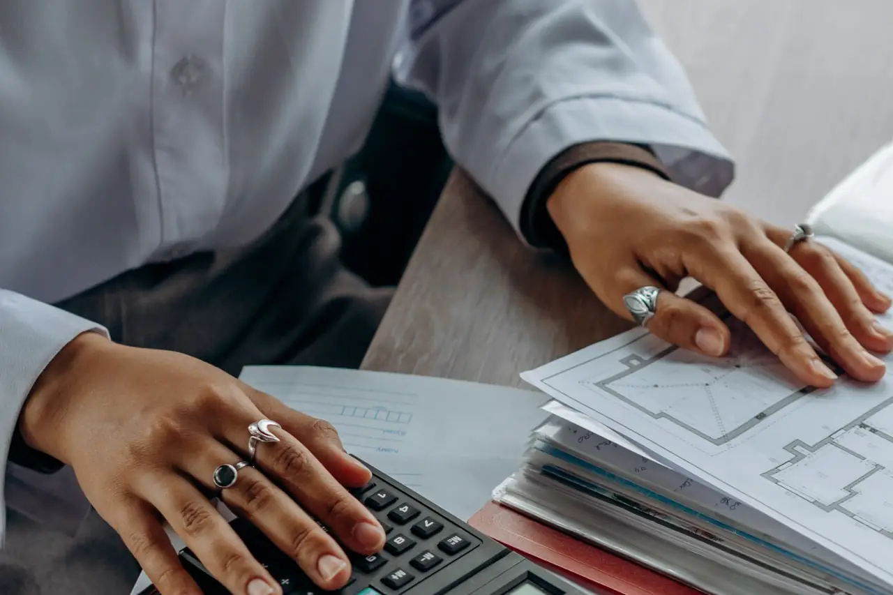 A person checking financial paperwork with a calculator
