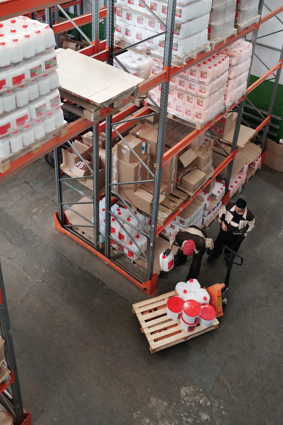 Warehouse colleagues checking stock beside shelves of supplies